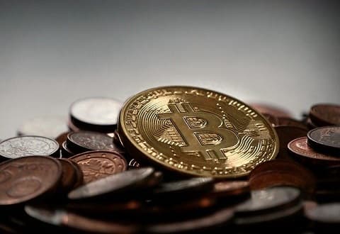 Bitcoin Münze zwischen Geldmünzen